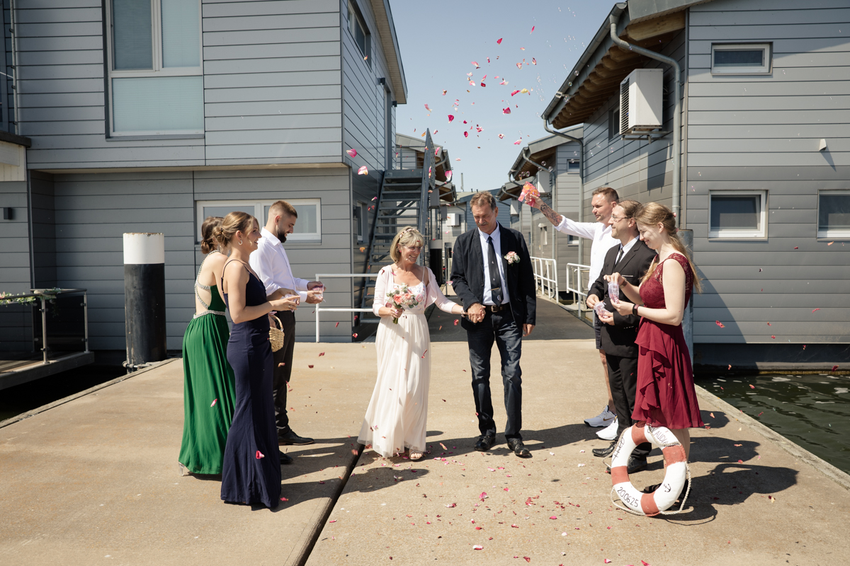 Brautpaar auf dem Steg mit Blütenblättern nach der Trauung
