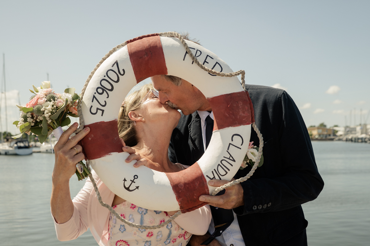 Brautpaar-Porträt mit Rettungsring und Hochzeitsdatum in der Marina Kröslin