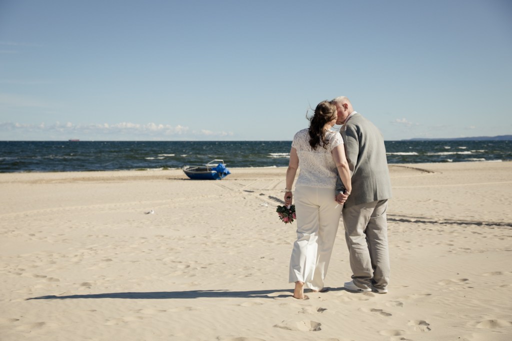 Brautpaar steht Hand in Hand am Strand von Ahlbeck nach der Trauung – barfuß im Sand und mit Blick auf die Ostsee.