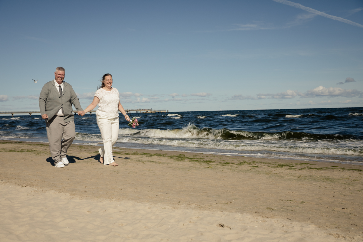 brautpaar läuft Hand in hand am Strand von Ahlbeck entlang
